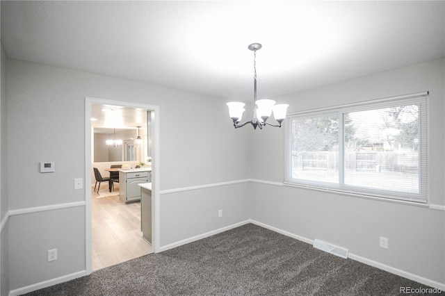 unfurnished room with visible vents, light carpet, baseboards, and a chandelier