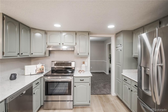 kitchen with under cabinet range hood, light countertops, gray cabinets, and appliances with stainless steel finishes