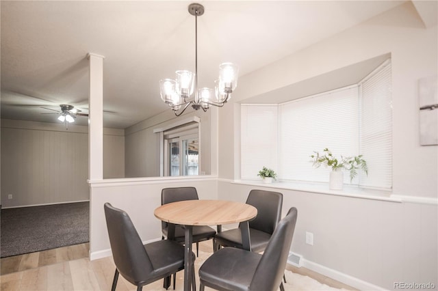 dining area featuring light wood finished floors and ceiling fan with notable chandelier