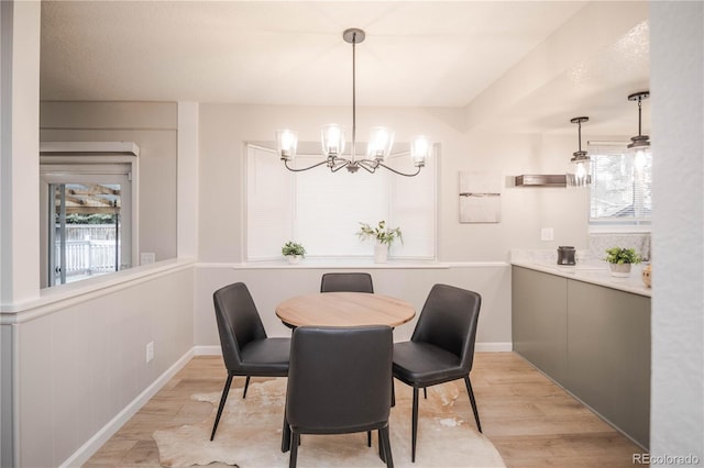 dining room with a chandelier, baseboards, and light wood-style floors