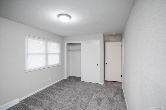 unfurnished bedroom with visible vents, a textured ceiling, a closet, carpet floors, and baseboards