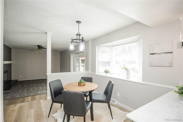 1409 S Moline St, Aurora, CO 80012 - dining space with light wood-style floors, a ceiling fan, a brick fireplace, and baseboards