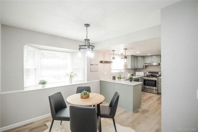 1409 S Moline St, Aurora, CO 80012 - dining space with light wood finished floors, a chandelier, and a wainscoted wall