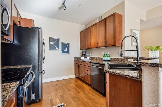 kitchen featuring black electric range oven, sink, light hardwood / wood-style flooring, stainless steel dishwasher, and dark stone countertops