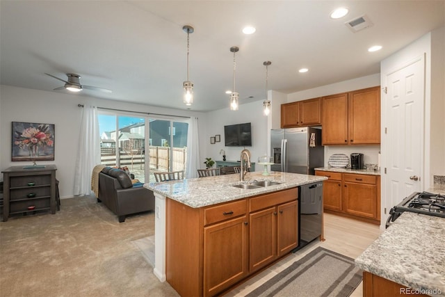 kitchen featuring brown cabinetry, dishwasher, open floor plan, stainless steel refrigerator with ice dispenser, and a sink