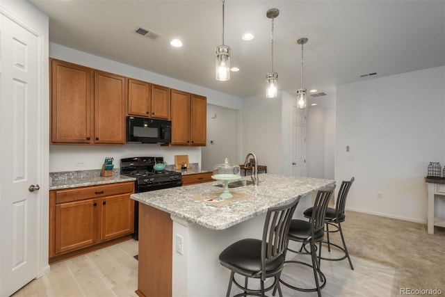 kitchen with black appliances, brown cabinetry, and visible vents