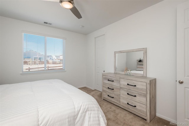 bedroom featuring baseboards, visible vents, a ceiling fan, and light colored carpet