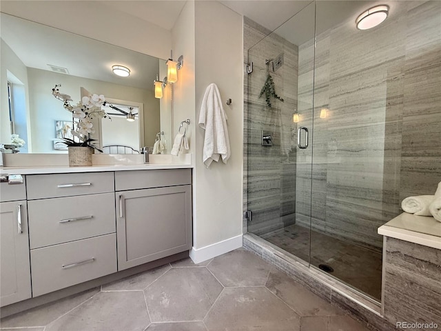 bathroom with a shower with door, vanity, and tile patterned floors