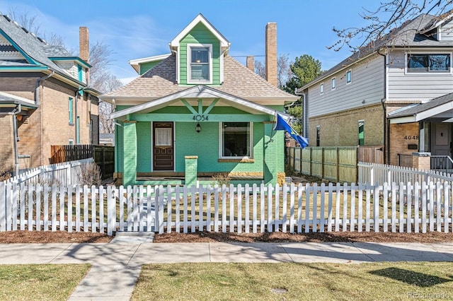 view of front facade featuring a fenced front yard, brick siding, a chimney, and a shingled roof