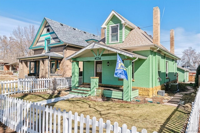 view of front of property with a fenced front yard, central air condition unit, brick siding, and covered porch