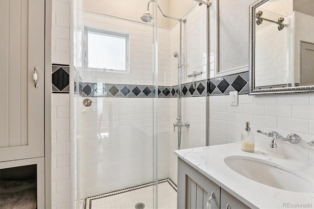 full bath with tile walls, a stall shower, and vanity