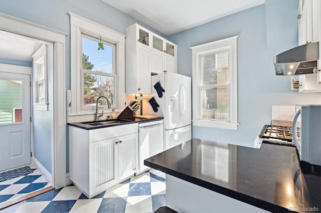 kitchen featuring white appliances, light floors, a sink, white cabinetry, and exhaust hood