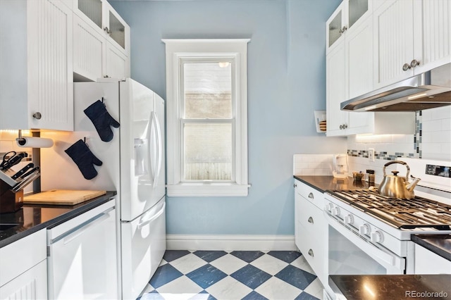 kitchen with dark countertops, light floors, white appliances, and under cabinet range hood