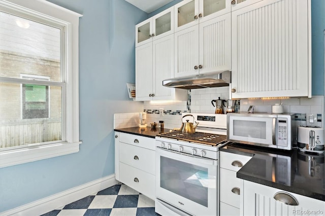 kitchen featuring tile patterned floors, white gas stove, under cabinet range hood, stainless steel microwave, and baseboards