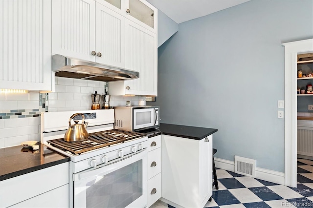 kitchen featuring visible vents, under cabinet range hood, decorative backsplash, tile patterned floors, and white appliances