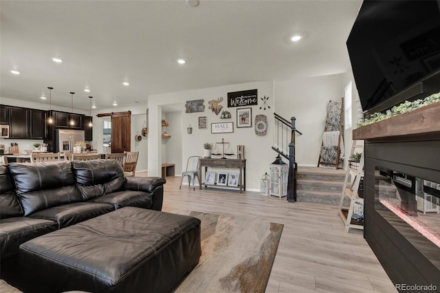 living room with a barn door and light hardwood / wood-style flooring