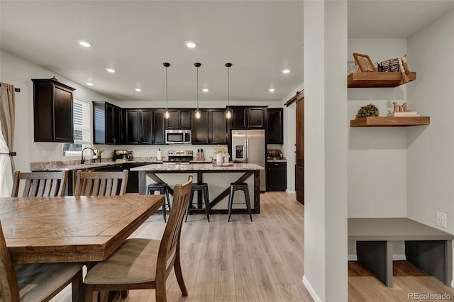 dining area with a barn door, light hardwood / wood-style floors, and sink