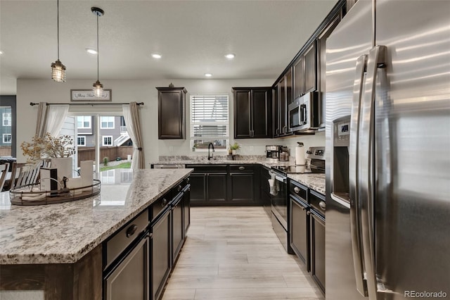 kitchen with sink, hanging light fixtures, dark brown cabinets, stainless steel appliances, and light stone countertops