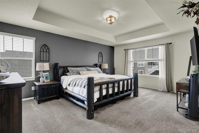 bedroom featuring light carpet and a tray ceiling