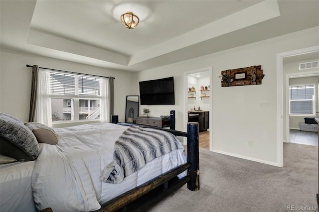 bedroom with multiple windows, a tray ceiling, and carpet floors