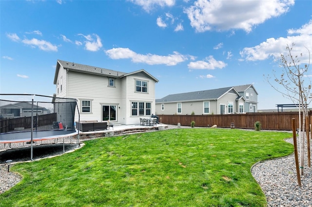 back of house with a trampoline, a patio area, and a lawn