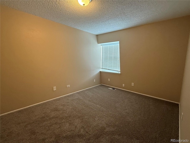 empty room with carpet flooring and a textured ceiling