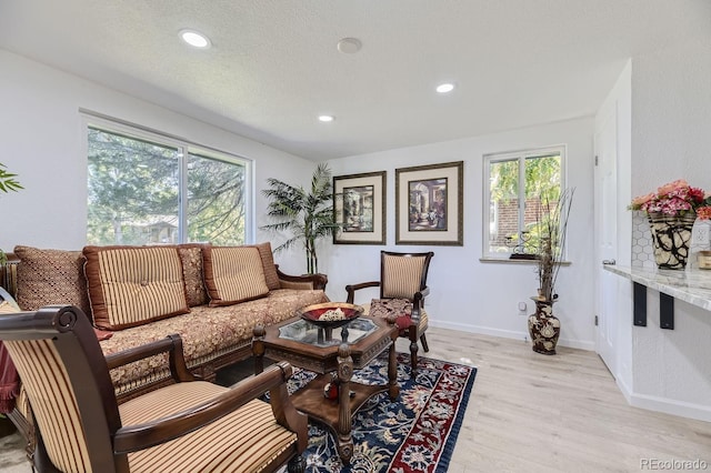 living area featuring light wood-style floors, recessed lighting, a textured ceiling, and baseboards