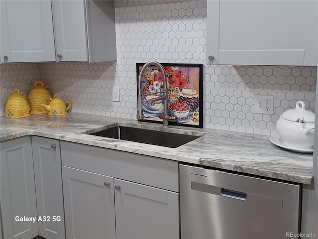 kitchen with light stone countertops, dishwasher, decorative backsplash, and a sink