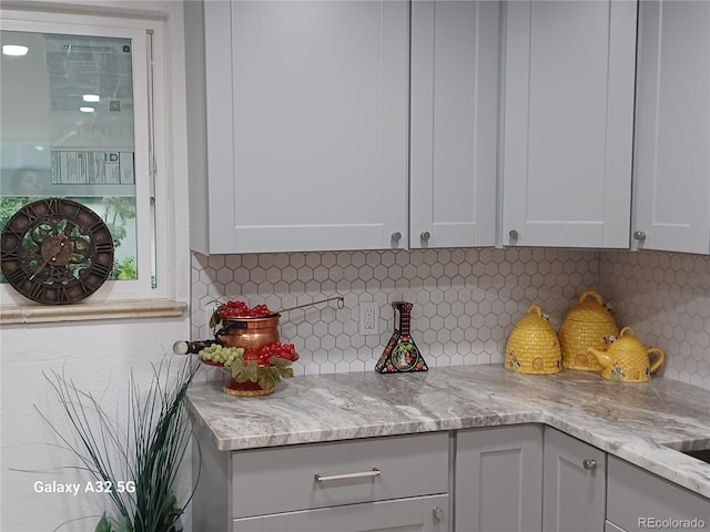 kitchen with light stone counters, white cabinetry, and tasteful backsplash