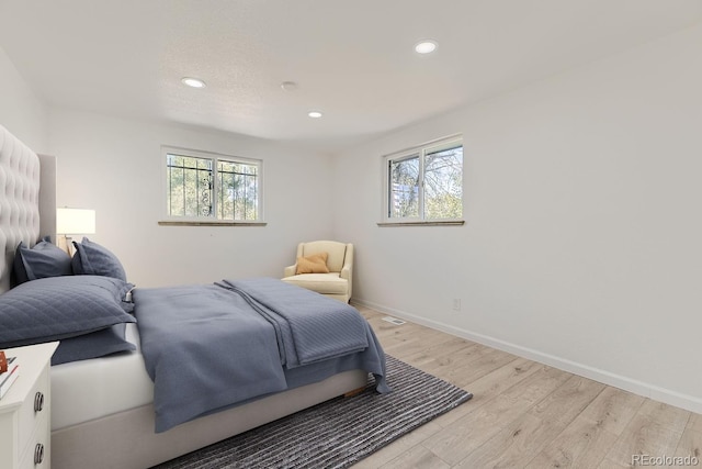 bedroom featuring baseboards, multiple windows, and light wood finished floors