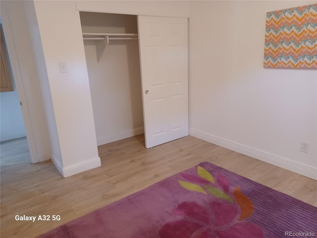 unfurnished bedroom with a closet, baseboards, and wood finished floors