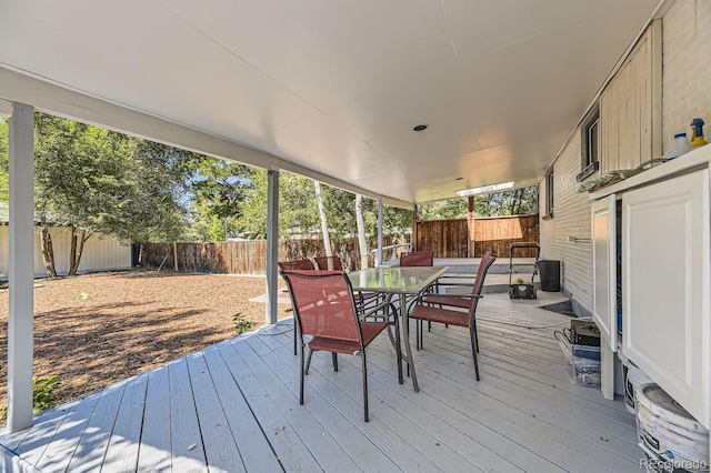 wooden terrace with a fenced backyard and outdoor dining space