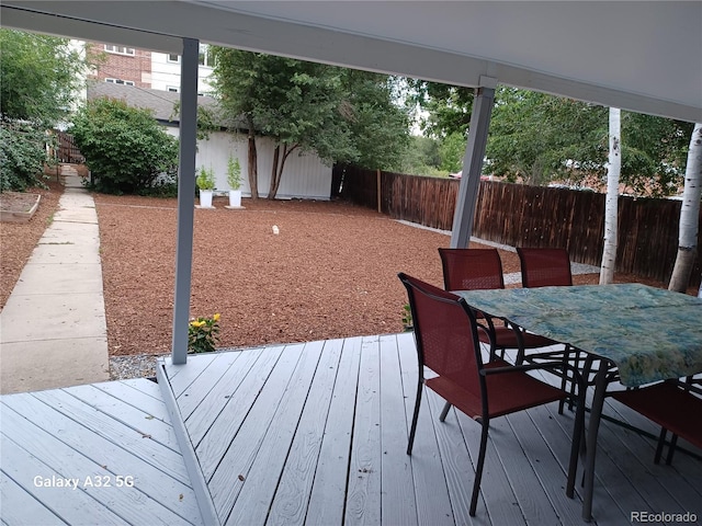 wooden terrace with outdoor dining space and a fenced backyard