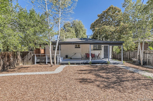 back of house featuring a deck, brick siding, and a fenced backyard