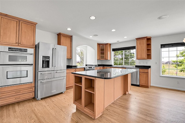 5131 Netherland St, Denver, CO 80249 - kitchen with open shelves, stainless steel appliances, arched walkways, light wood-style floors, and a center island