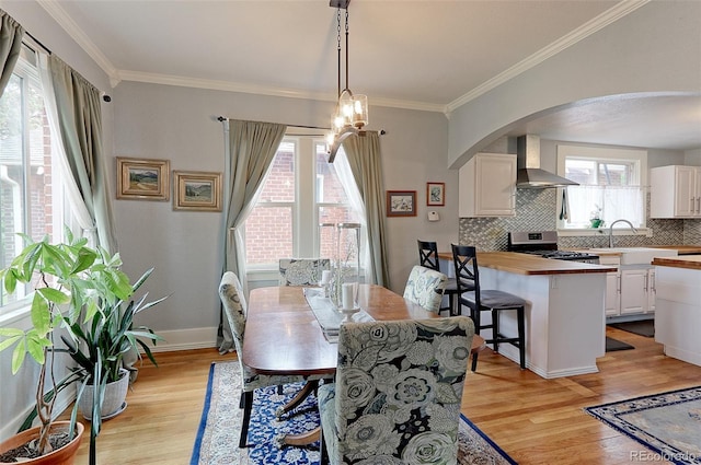 1434 Osceola St, Denver, CO 80204 - dining room with light wood-style floors, arched walkways, ornamental molding, and a chandelier