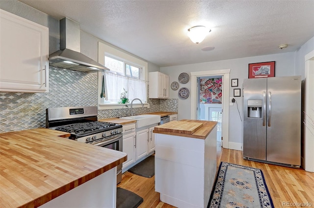 1434 Osceola St, Denver, CO 80204 - kitchen with wood counters, stainless steel appliances, wall chimney range hood, a sink, and light wood finished floors