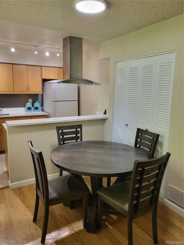 9105 E Lehigh Ave Unit 105, Denver, CO 80237 - dining area featuring light wood finished floors, a textured ceiling, and baseboards