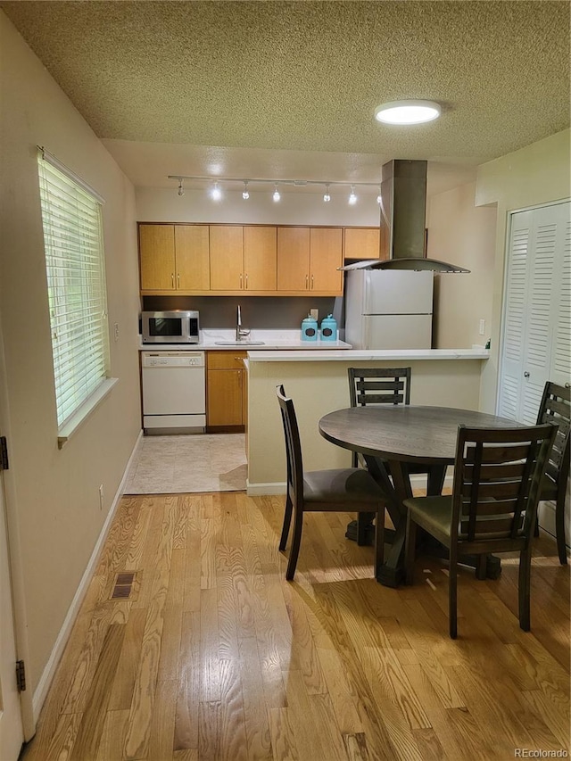9105 E Lehigh Ave Unit 105, Denver, CO 80237 - kitchen featuring white appliances, island exhaust hood, light wood finished floors, a textured ceiling, and a sink