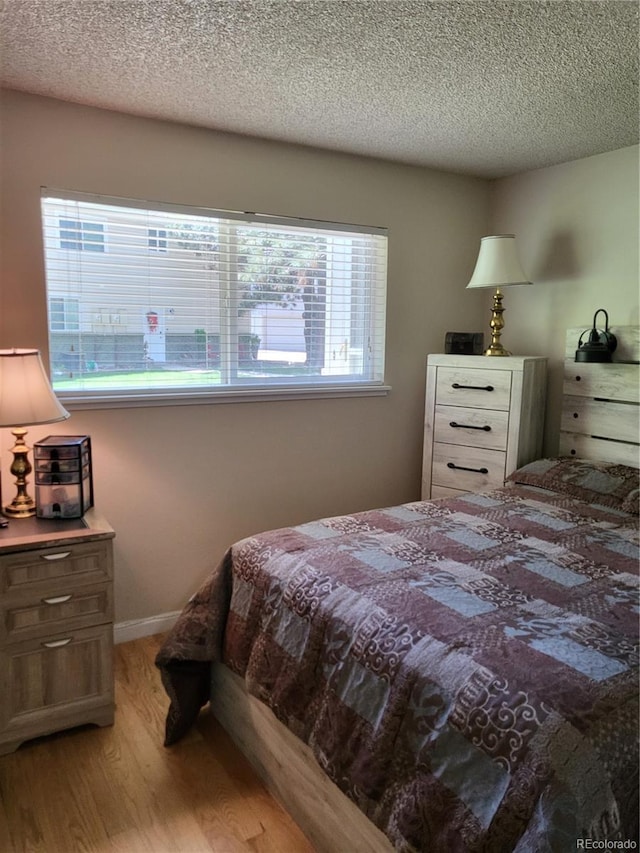 9105 E Lehigh Ave Unit 105, Denver, CO 80237 - bedroom featuring light wood finished floors and a textured ceiling