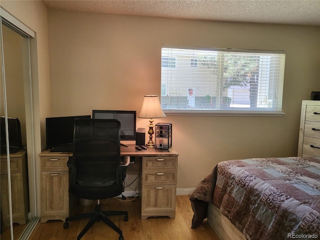 9105 E Lehigh Ave Unit 105, Denver, CO 80237 - bedroom with light wood-style floors, an office area, and a textured ceiling