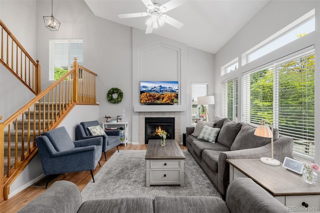 527 English Sparrow Trl, Highlands Ranch, CO 80129 - living area with high vaulted ceiling, stairs, wood finished floors, a tile fireplace, and a ceiling fan