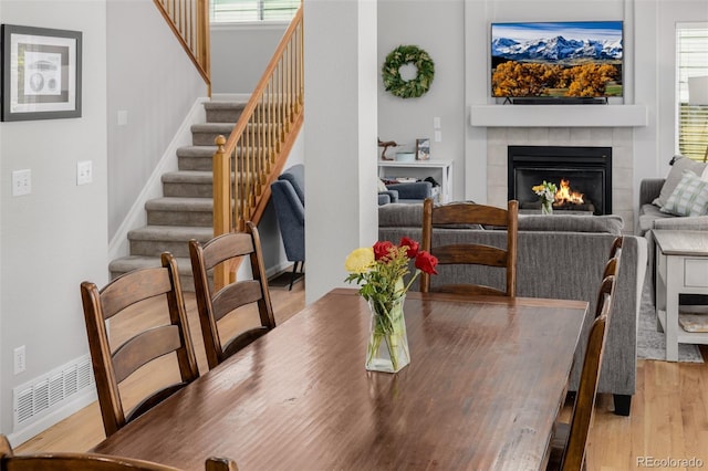 527 English Sparrow Trl, Highlands Ranch, CO 80129 - dining space featuring light wood-style floors, a tiled fireplace, stairway, and plenty of natural light