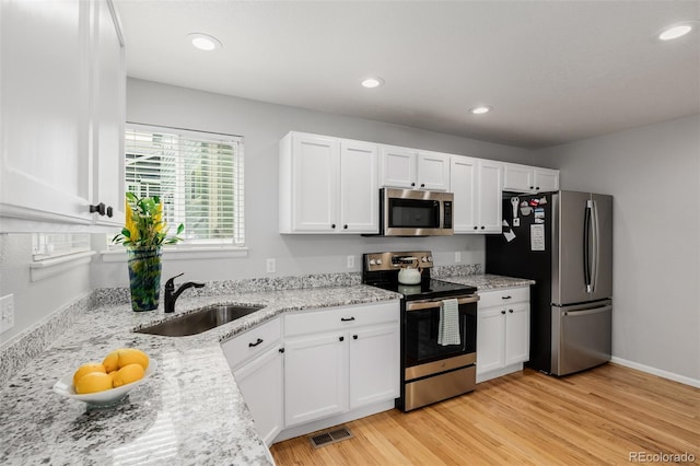 527 English Sparrow Trl, Highlands Ranch, CO 80129 - kitchen with appliances with stainless steel finishes, a sink, white cabinetry, light wood-style floors, and recessed lighting
