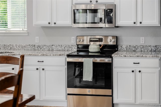 527 English Sparrow Trl, Highlands Ranch, CO 80129 - kitchen with appliances with stainless steel finishes, white cabinetry, and light stone countertops