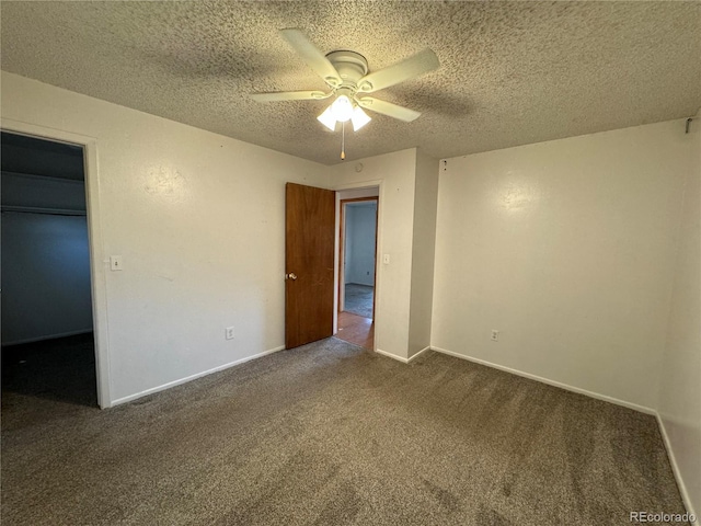 unfurnished bedroom with ceiling fan, a spacious closet, a closet, a textured ceiling, and carpet floors