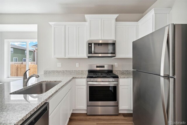 5913 Sawdust Dr, Brighton, CO 80601 - kitchen featuring appliances with stainless steel finishes, a sink, white cabinets, and dark wood-style flooring