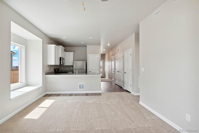 5913 Sawdust Dr, Brighton, CO 80601 - kitchen with stainless steel appliances, white cabinetry, carpet, and baseboards