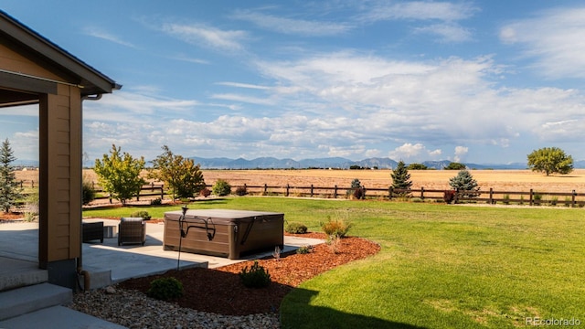 view of yard featuring a hot tub, a mountain view, a rural view, and a patio area