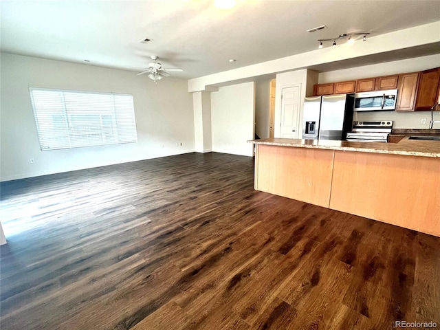 kitchen featuring rail lighting, sink, dark hardwood / wood-style floors, appliances with stainless steel finishes, and kitchen peninsula